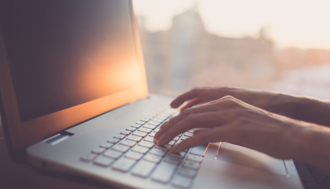 Woman typing on laptop at workplace working in home office hand keyboard.