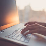 Woman typing on laptop at workplace working in home office hand keyboard.